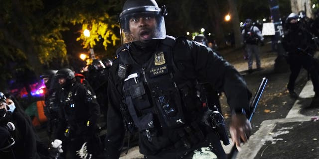 A Portland police officer pushes back protesters, Saturday, Sept. 26, 2020, in Portland. The protests, which began over the killing of George Floyd, often result frequent clashes between protesters and law enforcement. (AP Photo/John Locher)